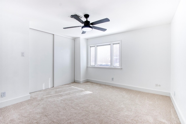 carpeted empty room with baseboards and a ceiling fan