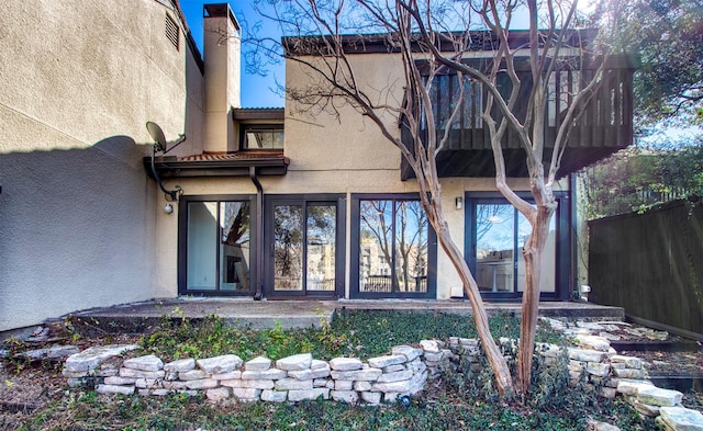 entrance to property with a chimney, fence, and stucco siding