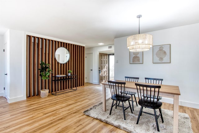 dining space featuring baseboards, a chandelier, and wood finished floors