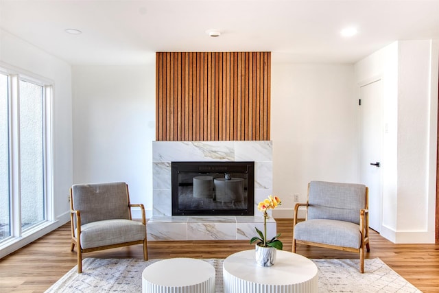 living area with a premium fireplace, recessed lighting, wood finished floors, and baseboards