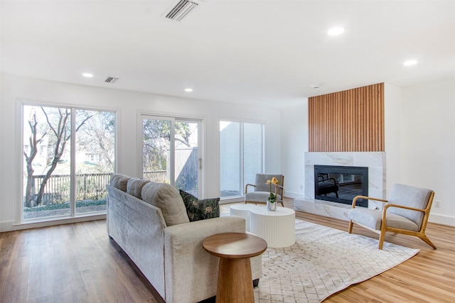 living room with recessed lighting, visible vents, a premium fireplace, and wood finished floors