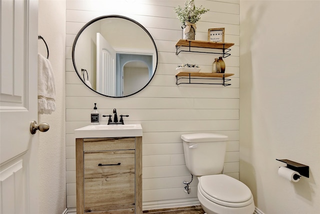 half bathroom featuring baseboards, vanity, and toilet