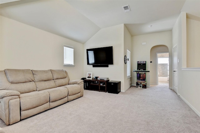 carpeted living area with lofted ceiling, plenty of natural light, visible vents, and arched walkways