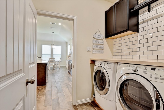 laundry area featuring wood finish floors, washer and clothes dryer, cabinet space, a sink, and baseboards