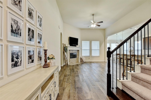 entryway featuring a premium fireplace, a ceiling fan, baseboards, stairs, and dark wood finished floors