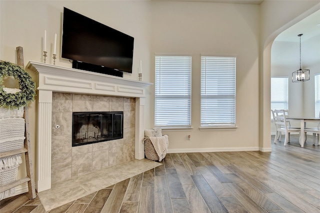 living room with an inviting chandelier, baseboards, wood finished floors, and a tile fireplace