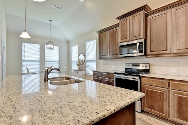 kitchen with visible vents, appliances with stainless steel finishes, a sink, light stone countertops, and backsplash