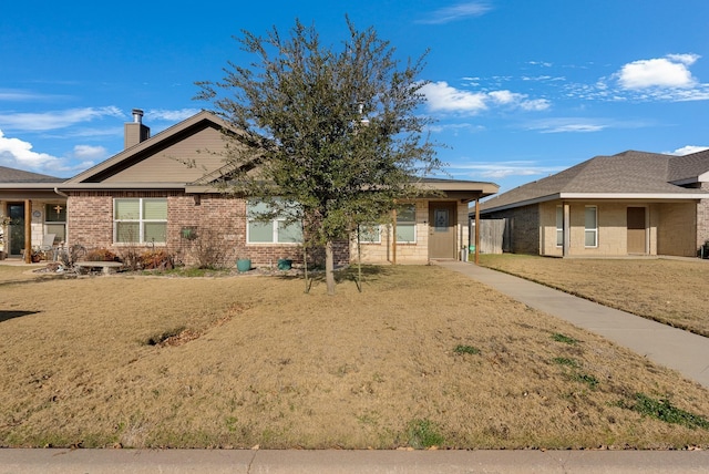 ranch-style house with a front yard, brick siding, and a chimney