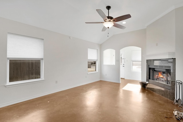 unfurnished living room with baseboards, a tiled fireplace, ceiling fan, vaulted ceiling, and concrete floors