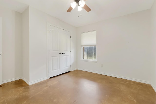 unfurnished bedroom with a ceiling fan, a closet, baseboards, and concrete flooring