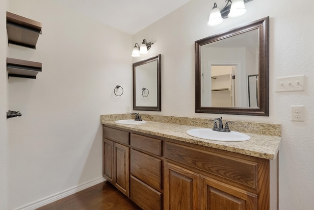 bathroom with double vanity, baseboards, and a sink