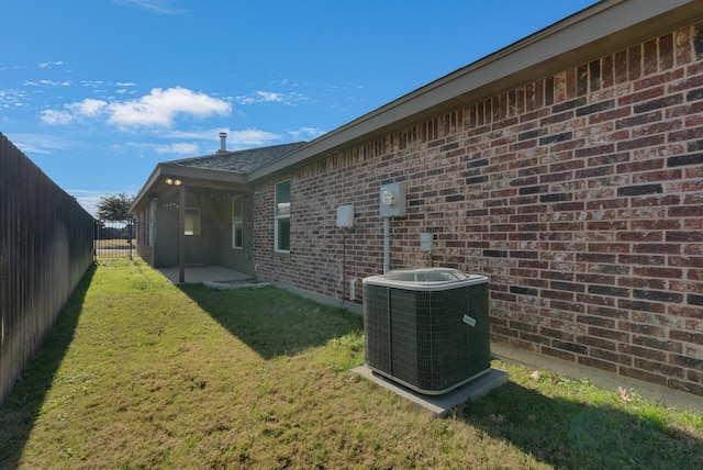 exterior space featuring central AC unit, a lawn, a fenced backyard, and brick siding