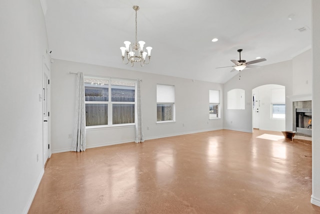 unfurnished living room with concrete flooring, ceiling fan with notable chandelier, baseboards, vaulted ceiling, and a tiled fireplace