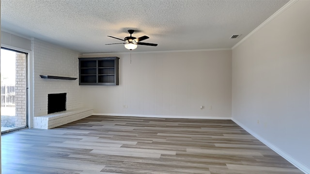 unfurnished living room featuring crown molding, visible vents, a brick fireplace, ceiling fan, and wood finished floors