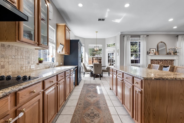 kitchen with light stone countertops, backsplash, a sink, and light tile patterned flooring