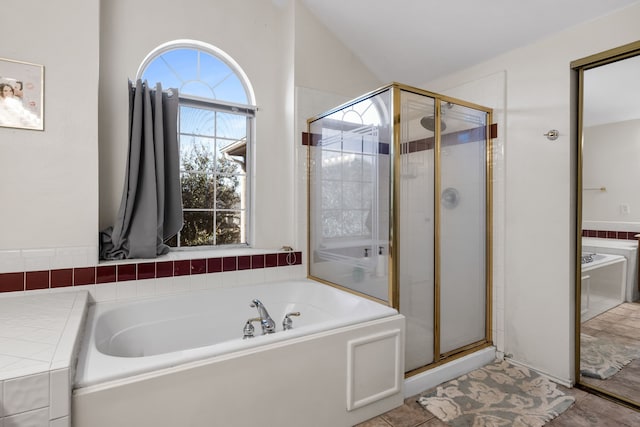 full bath with a stall shower, a garden tub, and vaulted ceiling