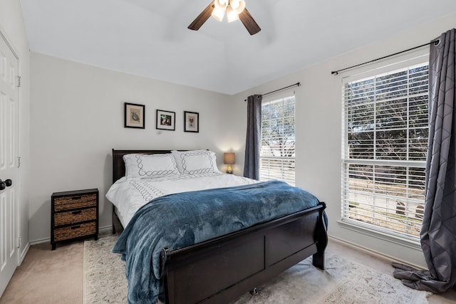 bedroom with lofted ceiling, baseboards, a ceiling fan, and light colored carpet