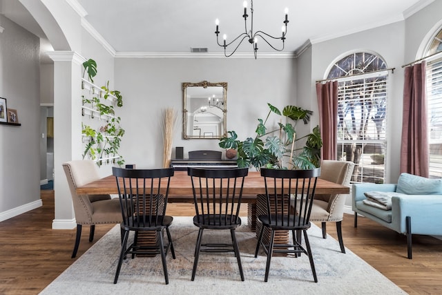 dining room featuring visible vents, arched walkways, wood finished floors, crown molding, and a notable chandelier