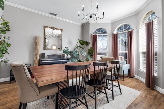 dining room with crown molding, wood finished floors, visible vents, and a notable chandelier