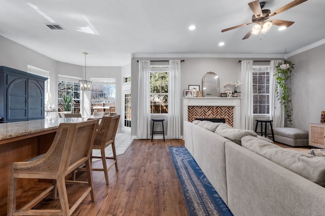 living room featuring recessed lighting, ceiling fan with notable chandelier, wood finished floors, visible vents, and crown molding