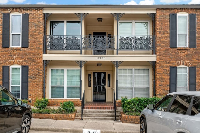 view of front of property featuring a balcony and brick siding