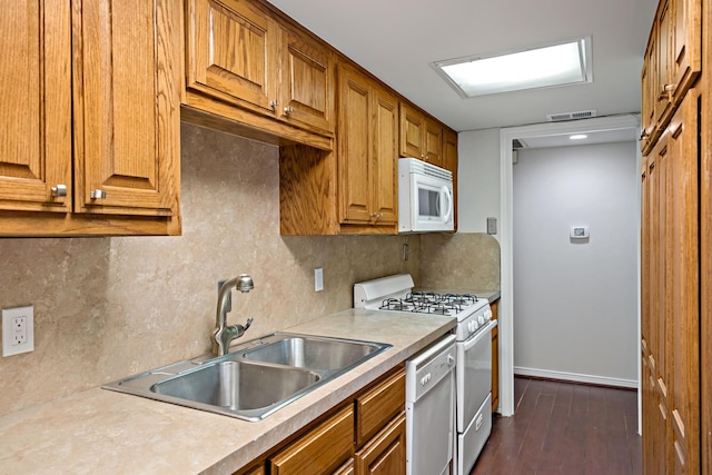 kitchen with visible vents, backsplash, brown cabinets, white appliances, and a sink