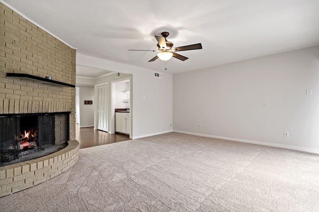 unfurnished living room featuring visible vents, carpet flooring, baseboards, a brick fireplace, and ceiling fan