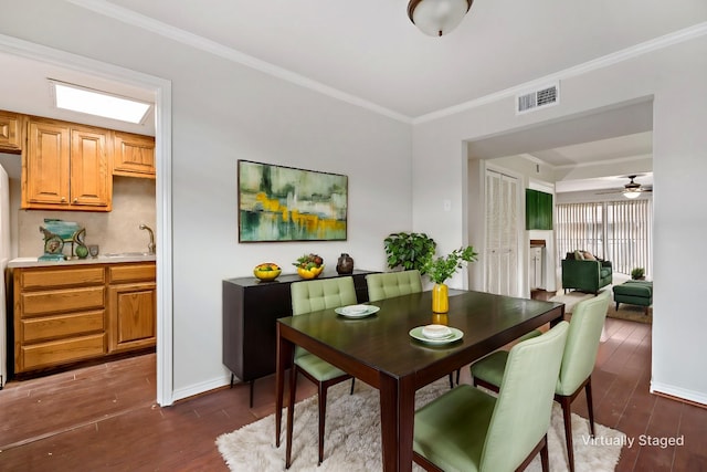 dining area featuring baseboards, visible vents, ceiling fan, ornamental molding, and dark wood-type flooring