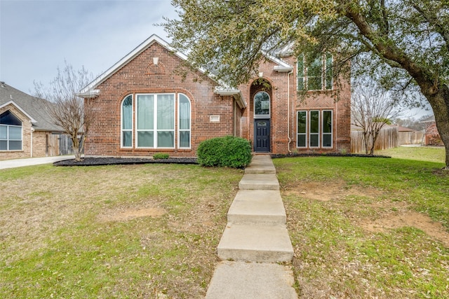 traditional-style home with a front yard, fence, and brick siding