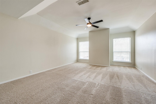 empty room featuring lofted ceiling, visible vents, a ceiling fan, light carpet, and baseboards