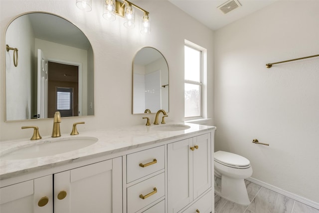 bathroom with visible vents, a sink, toilet, and double vanity