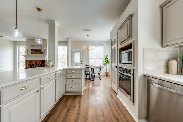 kitchen featuring appliances with stainless steel finishes, backsplash, dark wood-style flooring, a fireplace, and a wealth of natural light