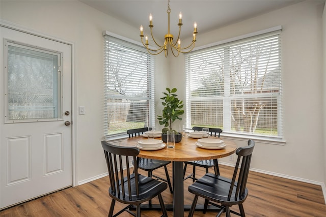 dining space featuring a chandelier, wood finished floors, and baseboards