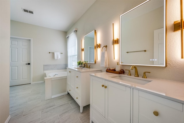 full bath featuring a bath, visible vents, two vanities, and a sink