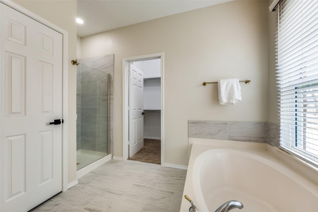 full bathroom featuring a garden tub, a shower stall, and baseboards