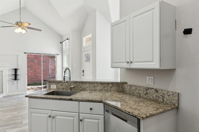 kitchen with vaulted ceiling, a sink, white cabinetry, and stainless steel dishwasher