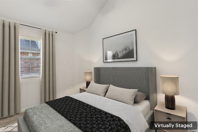 bedroom with vaulted ceiling and light wood-type flooring