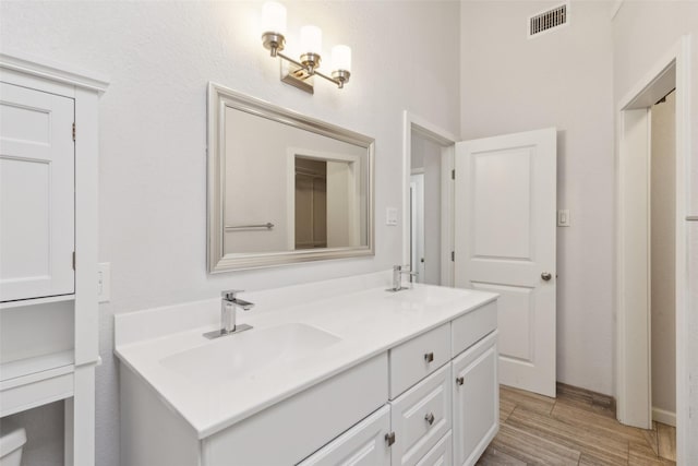 full bath with double vanity, wood finished floors, visible vents, and a sink