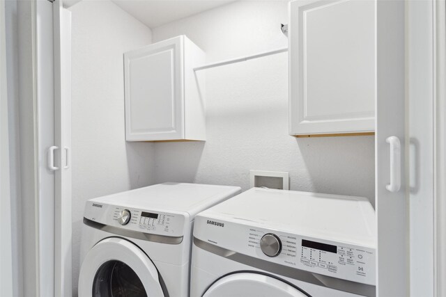 laundry area featuring cabinet space, a textured wall, and washer and clothes dryer