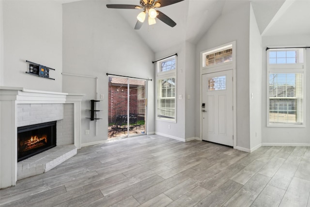 entrance foyer with plenty of natural light, high vaulted ceiling, wood finished floors, and a fireplace