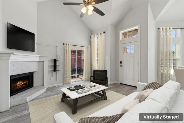 living room featuring a brick fireplace, wood finished floors, baseboards, and high vaulted ceiling