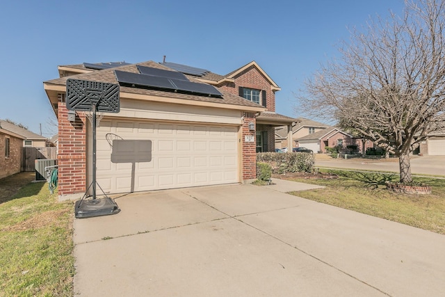 traditional-style home featuring a garage, roof mounted solar panels, brick siding, and concrete driveway