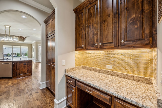 kitchen with light stone counters, tasteful backsplash, stainless steel dishwasher, and crown molding