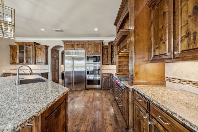 2161 Meadow View Dr, Prosper, TX 75078 - kitchen featuring built in appliances, tasteful backsplash, arched walkways, light stone countertops, and recessed lighting