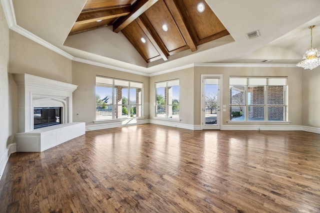 unfurnished living room featuring wood finished floors, visible vents, high vaulted ceiling, a glass covered fireplace, and a chandelier