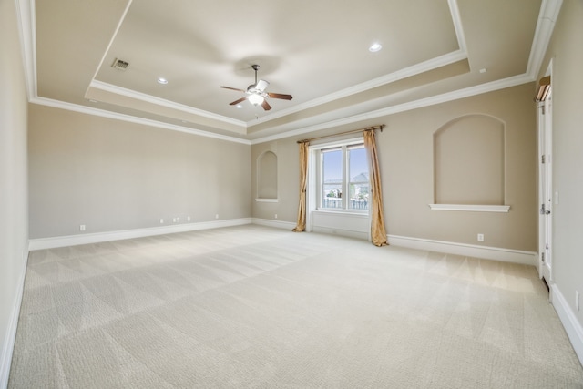 empty room featuring a tray ceiling, light carpet, and visible vents