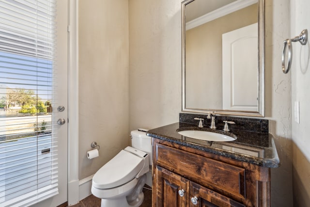 half bathroom featuring vanity, crown molding, and toilet