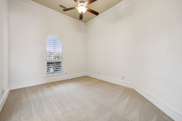 carpeted empty room with visible vents, ceiling fan, crown molding, and baseboards