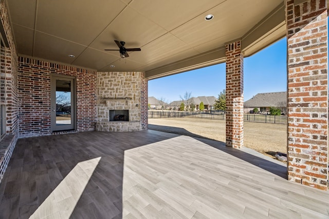 view of patio / terrace with an outdoor stone fireplace, a ceiling fan, and fence