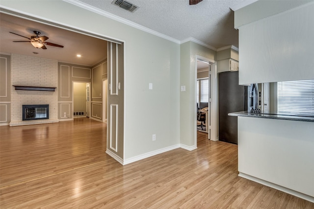 kitchen with visible vents, ceiling fan, freestanding refrigerator, crown molding, and light wood-type flooring